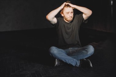 Çaresiz genç uyuşturucu bağımlısı karanlıkta tek başına oturuyor.