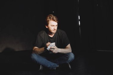 Kokain paketiyle yalnız oturan genç bağımlı adam.