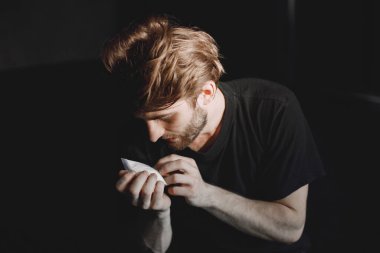 Kokain paketiyle yalnız oturan genç bağımlı adam.