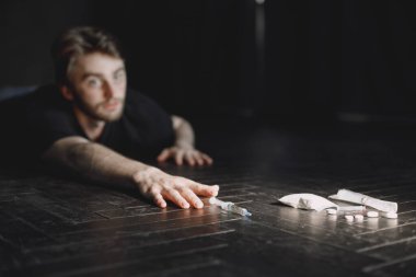 Keş adam şırıngaya uzanıyor.