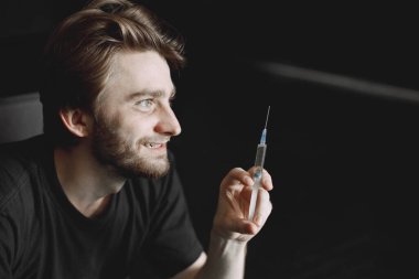 Uyuşturucu için şırınga tutan keş bir adam.