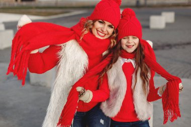 Kış parkında örgü şapkalı anne ve çocuk oynuyor.