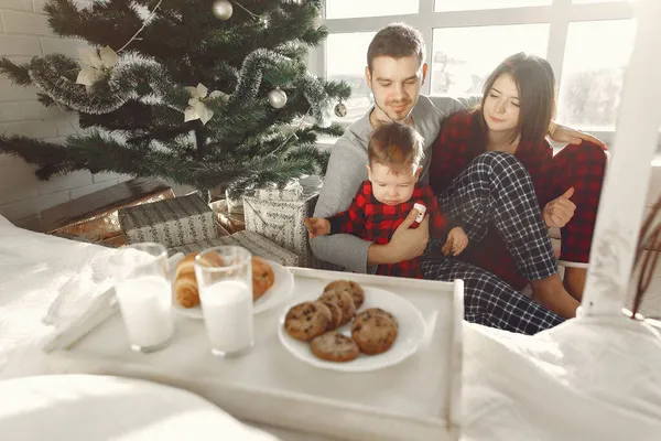 Hermosa familia sentada en la cama abrazando y comiendo galletas — Foto de Stock