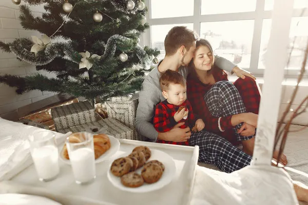 Hermosa familia sentada en la cama abrazando y comiendo galletas — Foto de Stock