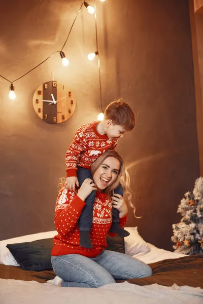 Madre en un suéter rojo con lindo hijo en casa — Foto de Stock