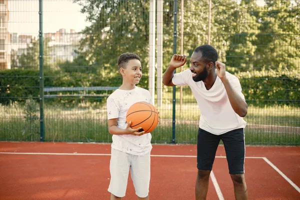 Pai negro com filho jogando basquete na quadra de basquete juntos — Fotografia de Stock