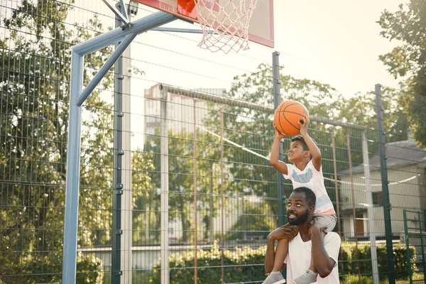 Jovem pai negro segurando nos ombros seu pequeno filho multiracional — Fotografia de Stock