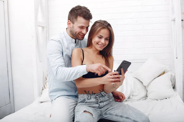 Пара, сидящая на кровати в комнате и пользоваться телефоном — стоковое фото