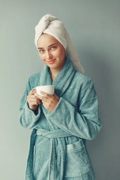 Schöne Mädchen steht in einem Studio in einem blauen Bademantel — Stockfoto