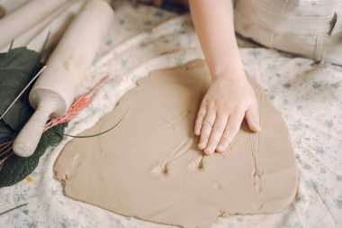 Küçük kız kilden bir tabak yapar ve onu süsler.