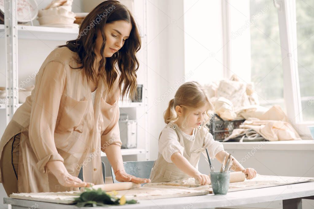 Portrait of mother and little girl shaping clay together
