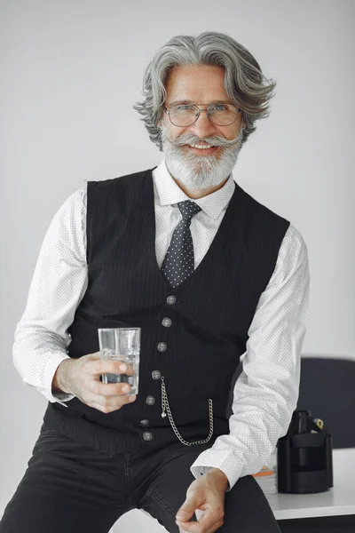 Przystojny stary biznesmen siedzi ze szklanką wody — Zdjęcie stockowe