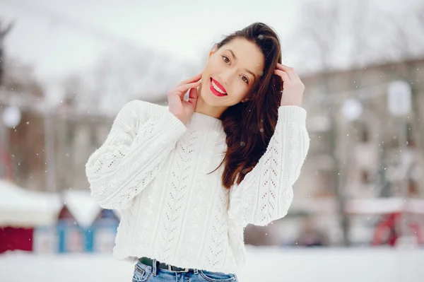 Молодая девушка в белом свитере стоит в зимнем парке — стоковое фото