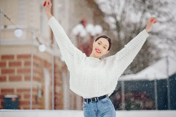 Junges Mädchen im weißen Pullover steht in einem Winterpark — Stockfoto