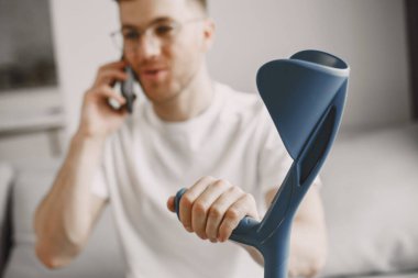 Elinde baston olan genç adam içeride telefonla konuşuyor.