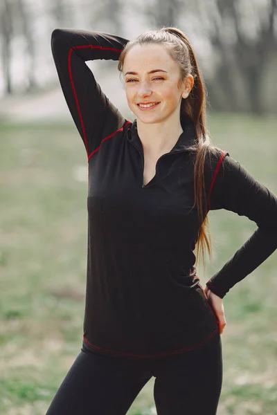 Mulher elegante em um uniforme preto em um parque de primavera — Fotografia de Stock
