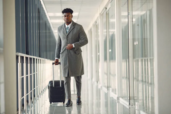 Elegante zwarte man op het vliegveld met een koffer — Stockfoto