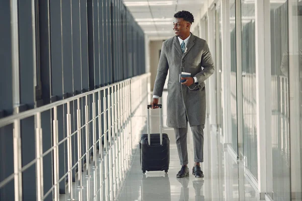 Eleganter schwarzer Mann mit Koffer am Flughafen — Stockfoto