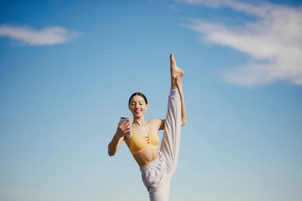 Linda chica con entrenamiento telefónico en un backgroung cielo —  Fotos de Stock