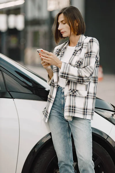 Ritratto di una giovane donna bruna che usa un cellulare vicino alla sua auto — Foto Stock