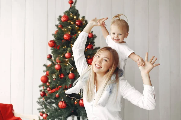 Madre con hija pequeña sentada junto al árbol de Navidad y divirtiéndose. — Foto de Stock