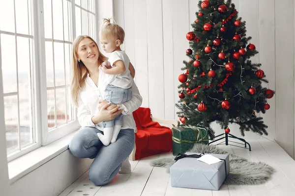 Madre con hija pequeña sentada junto al árbol de Navidad y divirtiéndose. — Foto de Stock