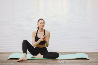 Su kenarında yoga yapan bir kadın.