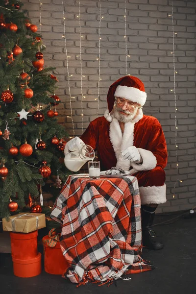 Człowiek w stroju Świętego Mikołaja znaleźć mleko i ciasteczka — Zdjęcie stockowe