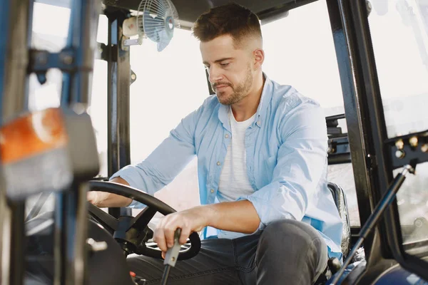 Hombre sentado cómodamente en un tractor azul grande — Foto de Stock