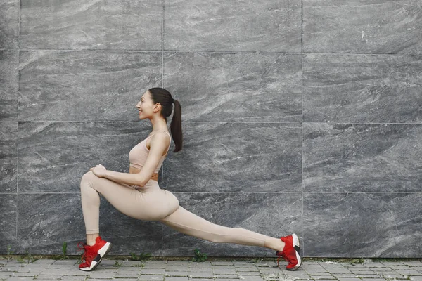 Woman practicing advanced yoga against a dark urban wall — Stock Photo, Image