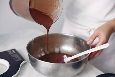 Beyaz elbiseli şef çikolatalı pasta hazırlıyor..