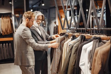 Üst düzey bir adam mağazadan yeni bir takım elbise seçiyor.