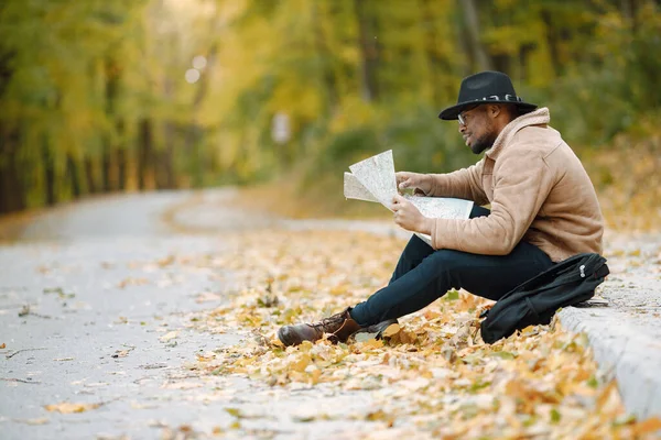 Чорний чоловік сидить на дорозі і дивиться на мапу — стокове фото
