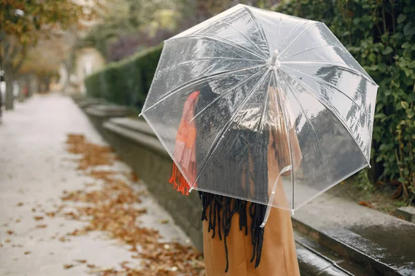 Rückseite Foto einer Frau im Mantel, die mit durchsichtigem Regenschirm nach draußen geht — Stockfoto