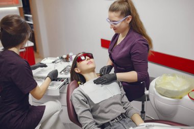 Güzel kız dişçi ofisinde oturuyor.