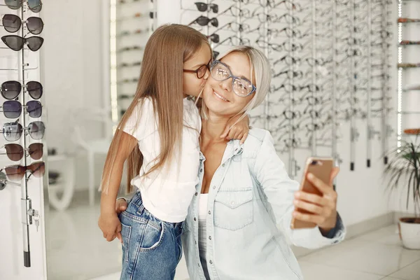 Family choosing glasses at optics store — Stockfoto