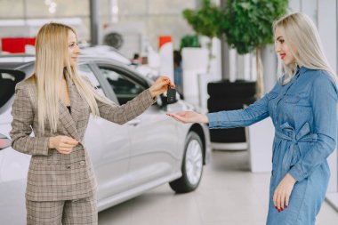 Bir araba galerisinde şık ve zarif kadınlar.