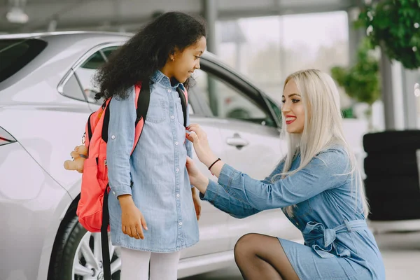 Caucasian mother with african daughter in a car salon — Photo