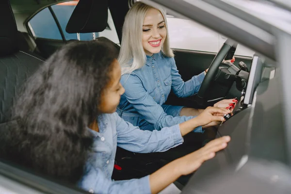 Caucasian mother with african daughter in a car salon — Stock Fotó