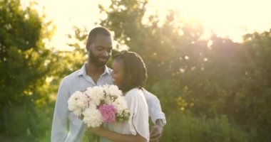 Black romantic couple with peony bunch in rural setting
