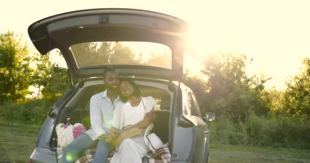 Lovely black couple sitting in a car trunk — Vídeos de Stock