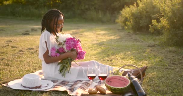 Black woman with peonies on a blanket — Stock Video