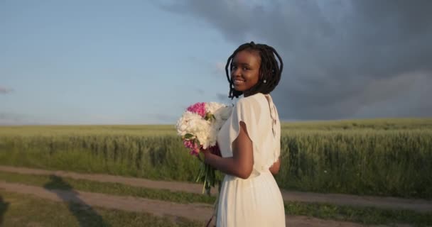 Beautiful black woman with flowers walk in the field — Wideo stockowe