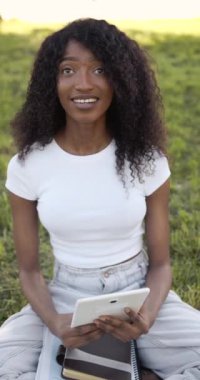 Outdoor portrait of a smiling black girl using a tactile tablet