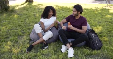 Multi cultural students drinking juice in park