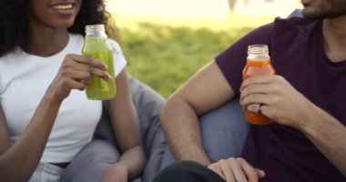 Cheerful young adults toasting with juice at park