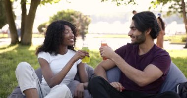 Multi cultural couple drinking juice in park