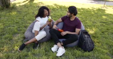 Multi cultural couple drinking juice in park
