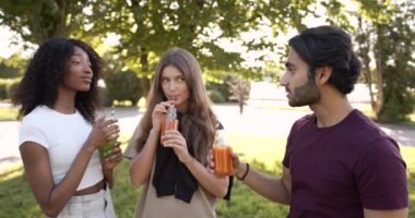 Multi cultural students drinking juice in park