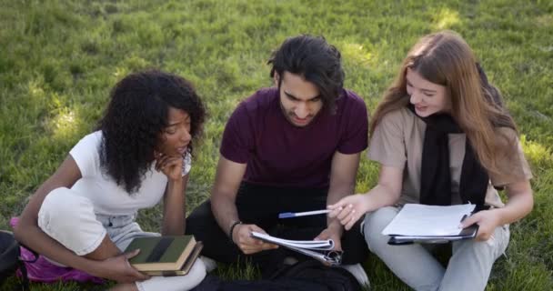 Students sitting on a lawn with books and learning — Vídeos de Stock